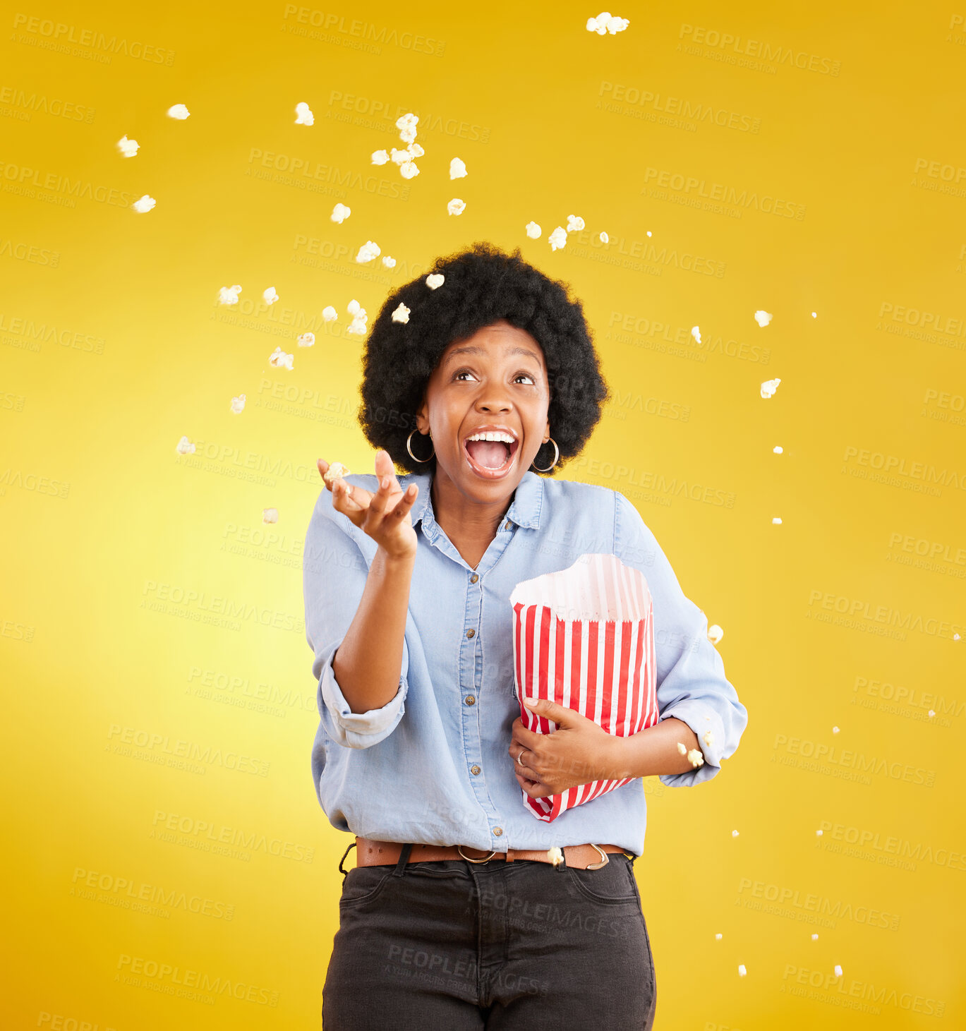 Buy stock photo Happy, throwing and popcorn with black woman in studio for movie, streaming service and cinema. Laugh, funny and theatre with female and snack isolated on yellow background for food, tv and film