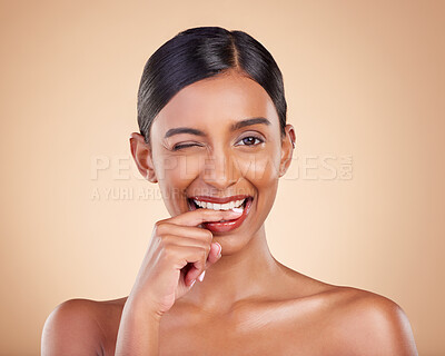 Buy stock photo Flirty, beauty and portrait of a winking woman isolated on a studio background. Happy, sexy and face of an Indian model with makeup, cosmetics and attitude on a backdrop to advertise lipstick