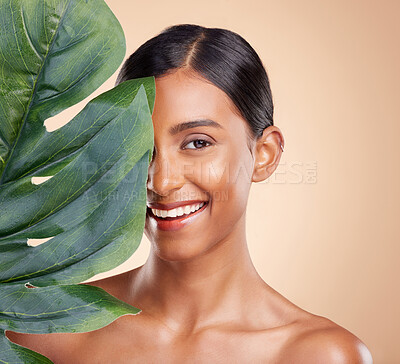 Buy stock photo Portrait, skincare and palm leaf with a model woman in studio on a beige background for natural beauty. Face, plants and nature with an attractive young female posing for cosmetics or luxury wellness