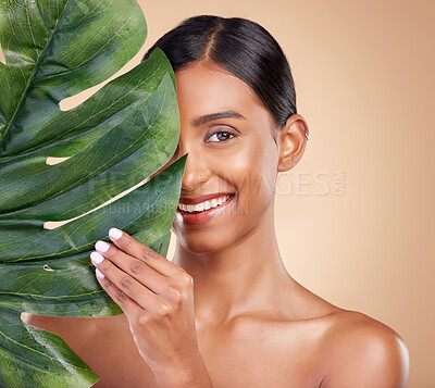 Portrait, facial and palm leaf with a model woman in studio on a beige background for natural skincare. Beauty, face and nature with an attractive young female posing for cosmetics or luxury wellness
