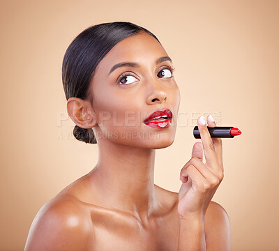 Buy stock photo Beauty, red lipstick and makeup on a woman in studio for cosmetics, skin glow and shine product. Indian female model thinking on beige background for skincare, facial self care and lips with color