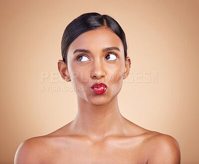 Buy stock photo Red lipstick, beauty and makeup on a woman in studio for cosmetics, skin glow and shine product. Indian female model thinking and kiss on beige background for skincare, self care and lips with color