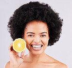 Portrait, skincare and orange by black woman in studio for vitamin c, wellness or skin detox on grey background. Face, fruit and girl model excited for citrus treatment, cosmetic or anti aging beauty