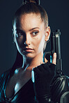 Woman, warrior and gun in studio with serious face for action, fight and safety from danger. Strong female model, assassin or agent in scifi leather cosplay costume with weapon on a dark background