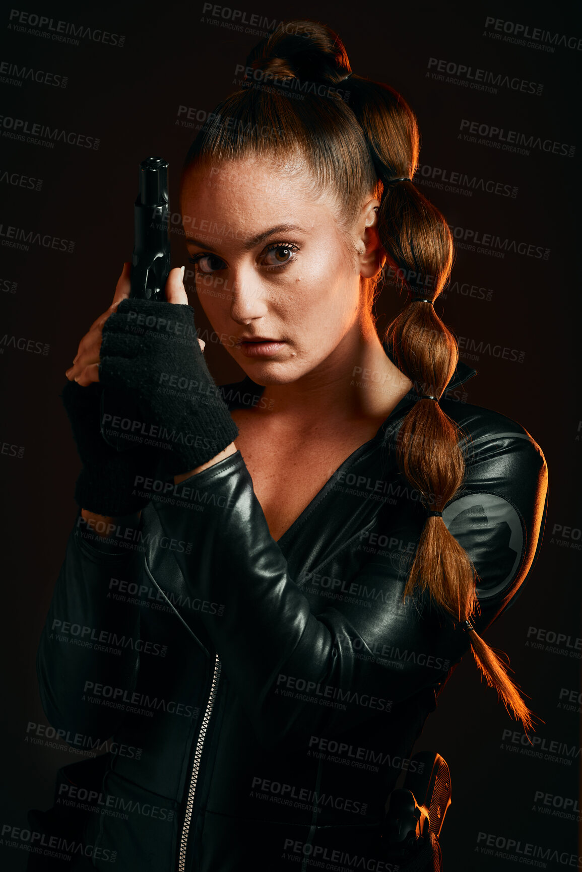 Buy stock photo Portrait, gun and spy with a woman assassin in studio on a dark background ready for combat. Hero, leather and power with an attractive young female secret agent holding a weapon on a mission