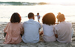 Family sitting on beach from the back, sunset and view of waves, zen and children playing in water together. Holiday, men and women relax in peace at evening ocean in Indonesia on tropical vacation.