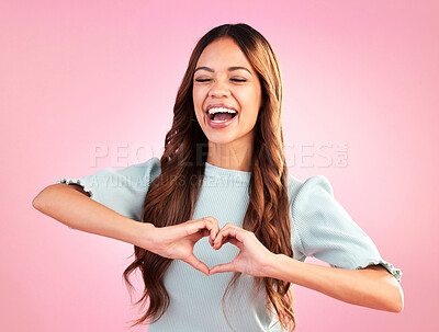 Buy stock photo Laugh, heart hands and happy with woman in studio for romance, positive and kindness. Love, support and emoji with female and shape isolated on pink background for emotion, hope and gesture 