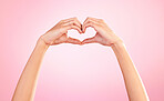 Love, heart and hands of woman in studio for romance, positive and kindness. Peace, support and emoji with female and shape isolated on pink background for emotion, hope and happiness gesture 