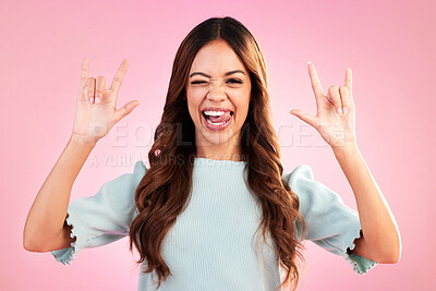 Buy stock photo Portrait of woman, rock hand gesture and wink in studio, heavy metal expression on face and pink background. Crazy, wild hispanic model and hands in devil horn sign with punk attitude and happy smile