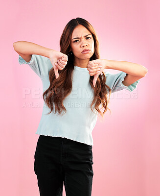 Buy stock photo Portrait, hands and thumbs down by sad woman in studio for bad review, complaint or disappointed on pink background. Face, finger and emoji expression by girl with vote for no, bad news or reject