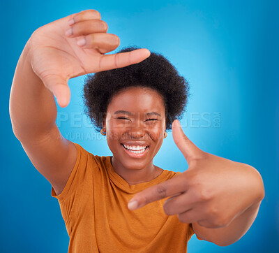 Buy stock photo Finger framing, portrait and happy black woman on blue background, studio and backdrop. Face, female and hands frame perspective, pose and smile of happiness, photography or capture profile picture