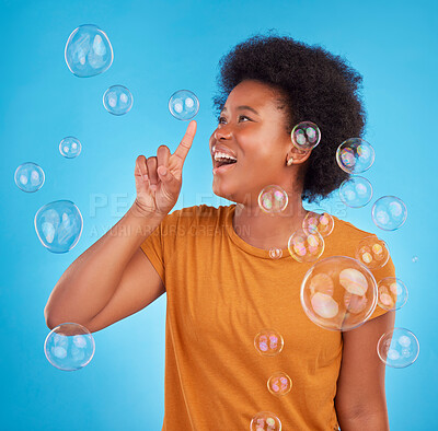 Buy stock photo Happy, bubbles and pop with black woman in studio for light, entertainment and satisfaction. Magic, rainbow and creative with female isolated on blue background for burst, happiness and color