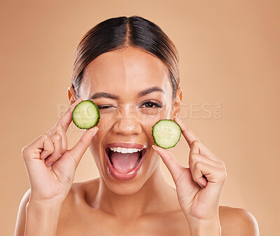 Buy stock photo Skincare, wink and portrait of woman with cucumber in hands for wellness, facial treatment and natural cosmetics. Beauty, spa and happy girl with fruit for detox, vitamin c and healthy skin in studio