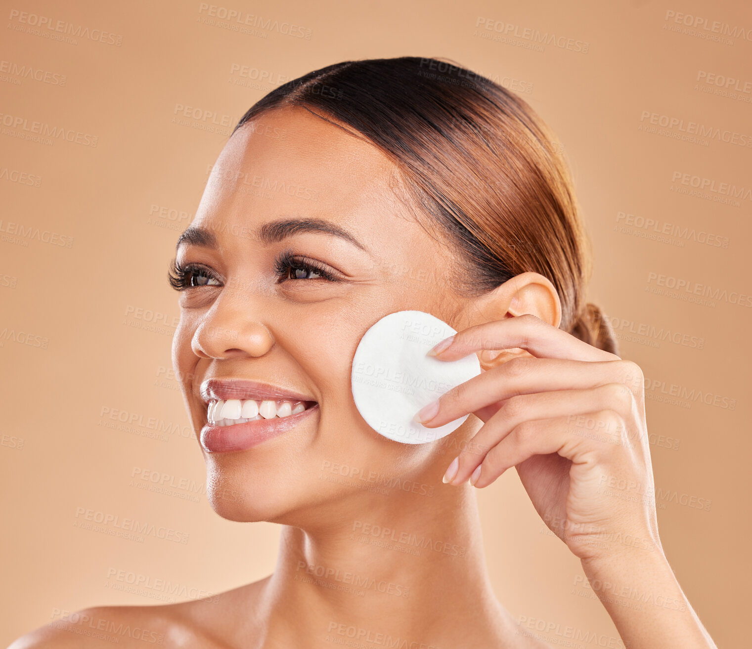 Buy stock photo Cotton, beauty and cleaning skin of woman in studio for dermatology, cosmetic and detox. Face and smile of female with hand for natural facial makeup clean, self care and skincare on brown background