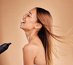 Beauty, woman and hair care with hairdryer in studio for growth or shine with strong texture. Happy aesthetic female laugh using blow dryer and heat protect for health and color on a brown background