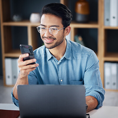 Buy stock photo Happy asian man, phone and laptop for social media, communication or networking at office desk. Male creative designer smiling with smartphone by computer for browsing, research or planning startup