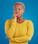 Nervous, worried and scared black woman in fear and bitting nails isolated against a studio blue background. Mental health, anxiety and anxious female in terror feeling confused, problem and crisis