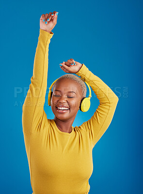 Buy stock photo Black woman with headphones, dance and listen to music with rhythm and fun with freedom on blue background. Happy female with arms raised, streaming radio with dancing and carefree in studio