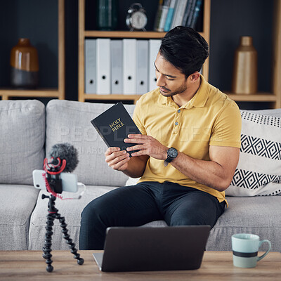 Buy stock photo Christian man, bible and study with phone and microphone online while live streaming. Asian male on home sofa with holy book on religion as blog content creator or influencer teaching on podcast