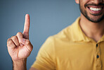 Asian man, hand and smile, pointing up in studio with mockup for choice or vote on blue background. Location, finger showing deal announcement or information with happy mock up space for notification