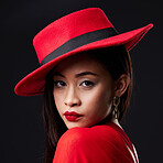 Portrait, red and fashion with a woman on a dark background in studio for contemporary style. Face, elegant and classy with an attractive young female model posing in modern designer clothes