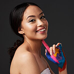 Beauty, woman and face, paint on hand with art, colorful aesthetic and happiness in portrait on studio background. Skin, glow and cosmetics with creativity and female with smile, manicure and nails