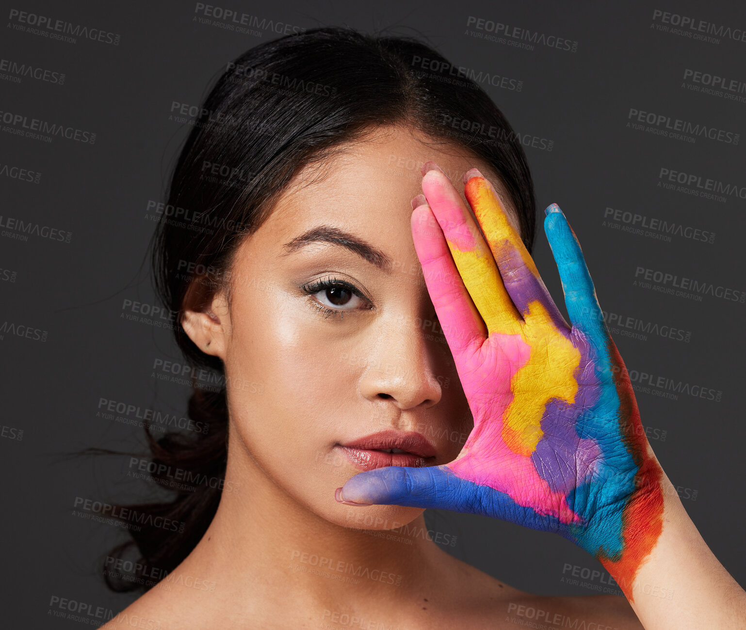 Buy stock photo Beauty, woman and face, paint on palm with art, colorful aesthetic and makeup with color in portrait on studio background. Skin, glow and cosmetics, creativity and female hand with artistic