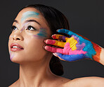 Woman, hand and beauty with rainbow paint art and face thinking in studio. Creative skin and makeup on female aesthetic model on gray background for lgbtq color inspiration and hope or peace on hands