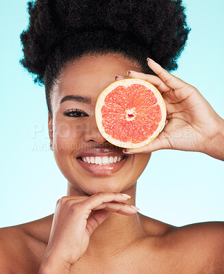 Buy stock photo Black woman, face and grapefruit for skincare nutrition, beauty or vitamin C against a blue studio background. Portrait of African American female smile with fruit for natural health and wellness