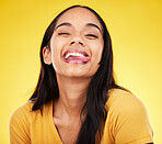 Woman, portrait smile and tongue out with silly facial expression against a yellow studio background. Happy, fun and goofy carefree female model smiling with teeth and funny face in joyful happiness