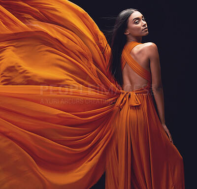 Buy stock photo Fashion, woman and elegant, dress flying and style, beauty on dark background, portrait and model in orange in studio. Indian female, glamour and stylish with sexy person, luxury and designer wear