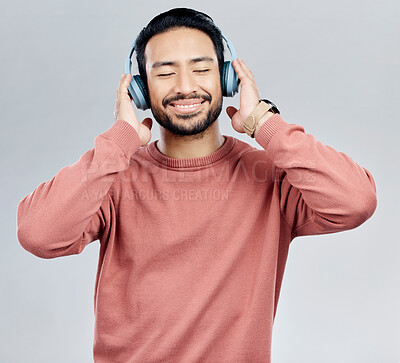 Buy stock photo Listen, happy and Asian man with headphones, streaming music and sounds against a white studio background. Japan, male and guy with headset, listening to radio and podcast for motivation and wellness