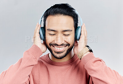 Buy stock photo Happy, music and Asian man with headphones, streaming and cheerful on a grey studio background. Japan, male and confident guy with headset, listening to audio and sounds for peace, smile and wellness