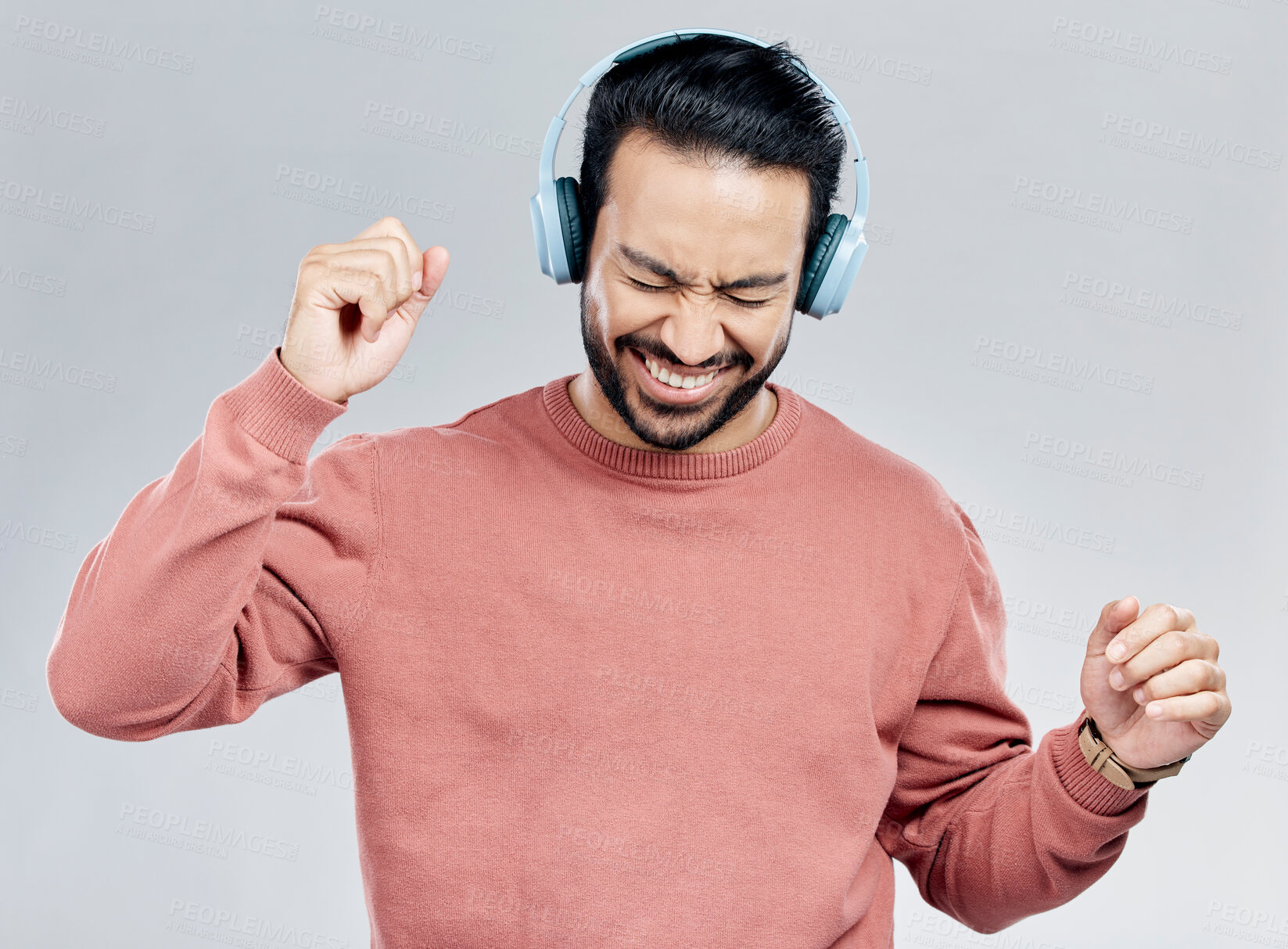 Buy stock photo Fun, dance and Asian man with headphones, streaming music and happiness against a grey studio background. Japan, male and guy with headset, listening radio and sounds with movement, silly and smile
