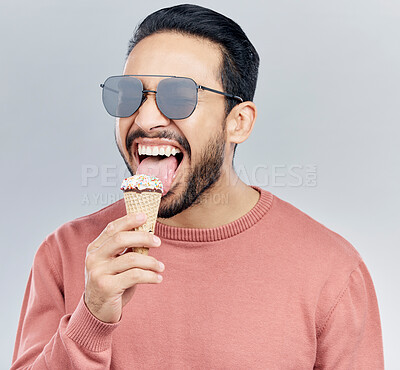 Buy stock photo Summer, sunglasses and ice cream with a man in studio on a gray background enjoying a sweet, treat or snack. Food, fashion and dessert with a handsome young male eating or licking an icecream cone 