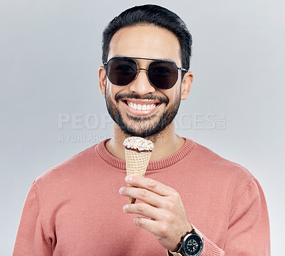 Buy stock photo Portrait, sunglasses and ice cream with a man in studio on a gray background enjoying a sweet snack in summer. Food, fashion and dessert with a handsome young male eating or licking an icecream cone 