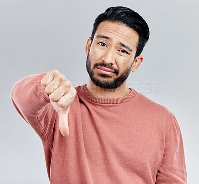 Buy stock photo Sad, disappointment and portrait of an Asian man with a thumbs down isolated on a studio background. Review, unhappy and a Chinese guy with a hand sign for a problem, mistake and dislike emoji