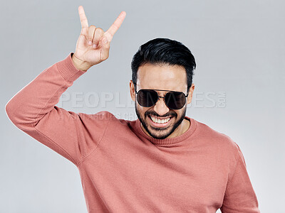 Buy stock photo Portrait, rock on and hand gesture with a man in studio on a gray background feeling crazy or energetic. Face, rocker or hardcore and a male posing with a devil horns sign or symbol at a concert