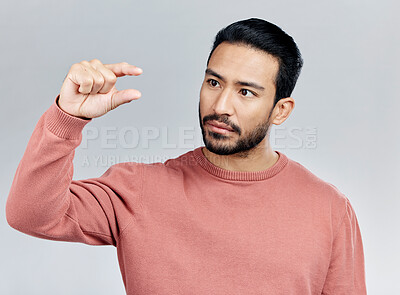 Buy stock photo Little, small sign and hand of man in studio on white background to measure size, scale and height. White background, mockup space and serious male with gesture for review, feedback and tiny symbol