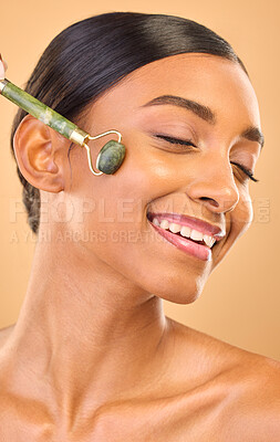 Buy stock photo Woman, face and beauty, roller and skincare, smile and facial massage on studio background. Jade quartz cosmetic tools, dermatology and skin glow, happy Indian female and self care with cosmetics