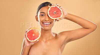 Buy stock photo Indian woman, grapefruit and beauty with face in portrait, natural cosmetics and organic treatment on studio background. Skincare, healthy glow and female smile with fruit product, skin and mockup