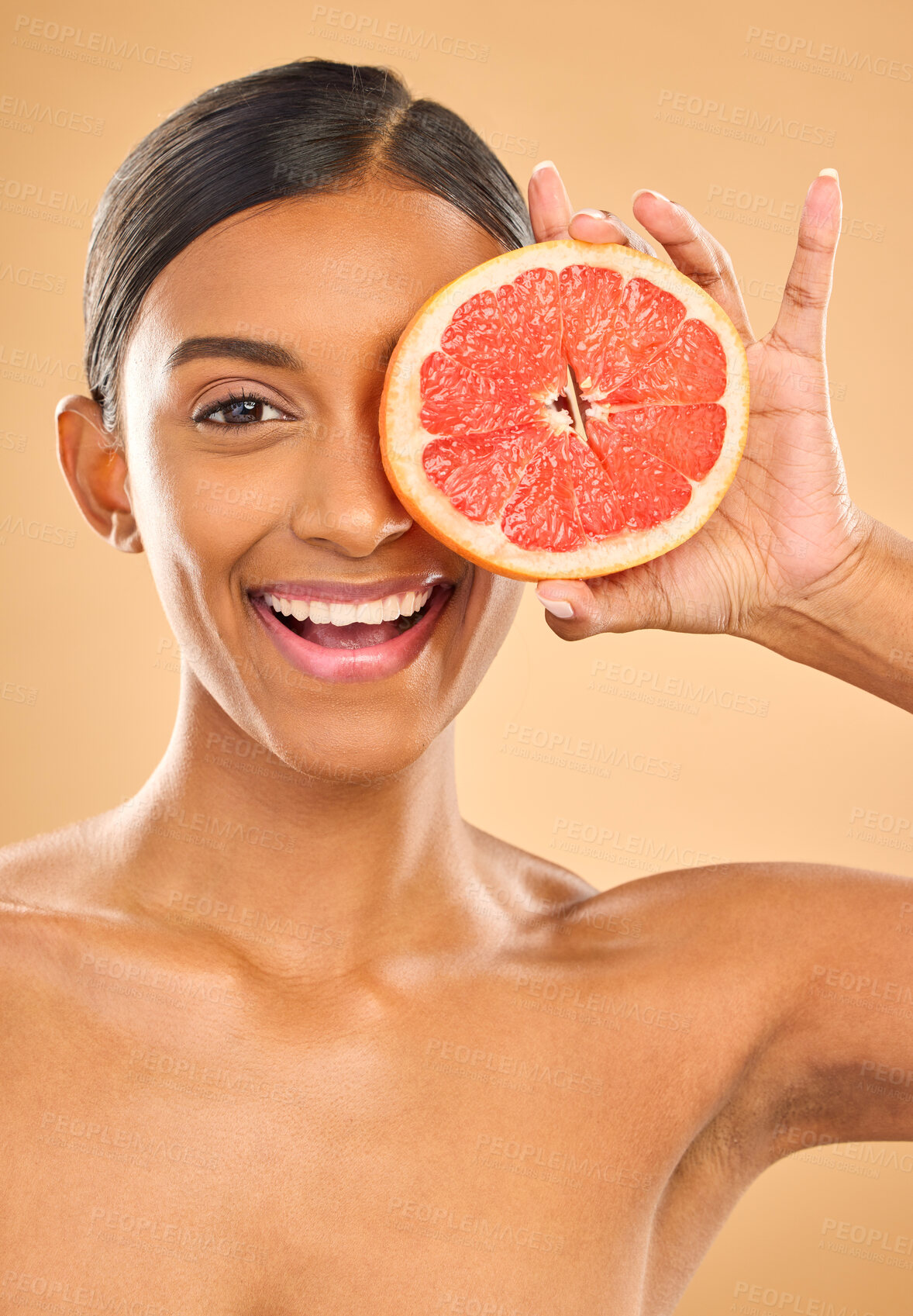 Buy stock photo Face smile, skincare and woman with grapefruit in studio isolated on a brown background. Portrait, natural cosmetics and happy Indian female model with citrus fruit for vitamin c, nutrition or beauty