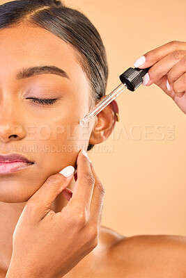 Buy stock photo Face, skincare serum and woman with eyes closed in studio isolated on brown background. Dermatology, cosmetics and Indian female model apply hyaluronic acid, retinol or essential oil for healthy skin