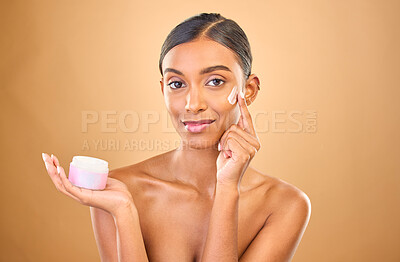 Buy stock photo Face, skincare and woman with cream jar in studio isolated on a brown background. Dermatology cosmetics, portrait and happy Indian female apply lotion, creme and moisturizer product for healthy skin.
