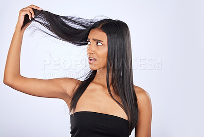 Hair damage, breakage and shock of a frustrated woman isolated on a white background in studio. Bad, unhappy and an Indian girl sad about split ends, holding tangled hairstyle and frizzy haircare