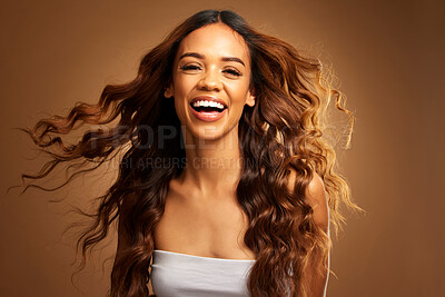 Portrait, hair and salon with an excited woman on a brown background in studio for natural haircare. Face, smile and shampoo with an attractive young female feeling happy about keratin treatment