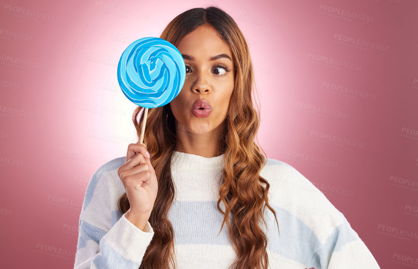 Buy stock photo Portrait, funny face and lollipop with a woman on a pink background in studio holding giant candy. Comic, comedy and sweet with a playful young female feeling silly while eating a blue sugar treat 