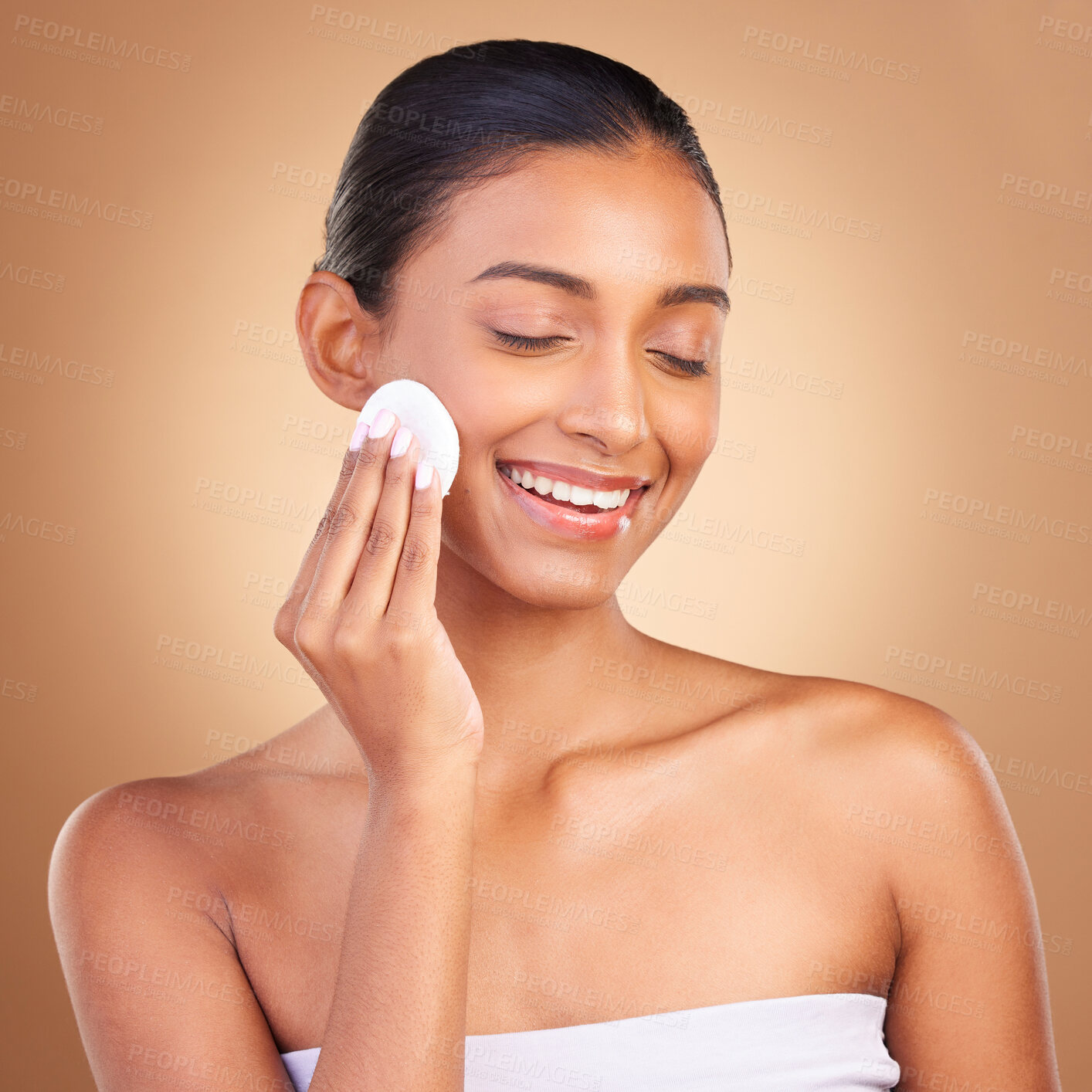 Buy stock photo Beauty, skincare and cotton with indian woman and product in studio for self care, makeup remover and cosmetics. Happy, pad and glow with model on brown background for results, natural and facial