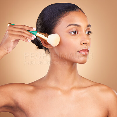 Buy stock photo Makeup, product and brush with indian woman in studio for foundation, blush and self care. Glow, cosmetics and facial with female model isolated on brown background for shine, clean and confidence