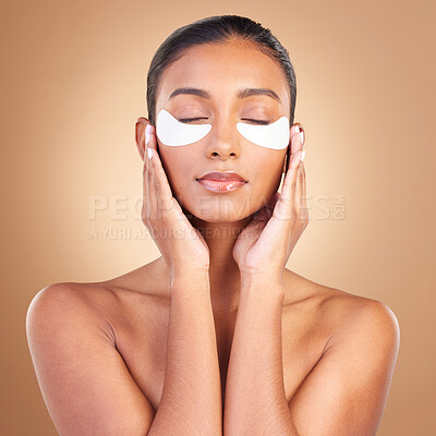 Buy stock photo Skincare, eye patch and touch with Indian woman in studio for facial, spa treatment and glow. Self care, cosmetics and hydration with female model on brown background for mask, product and youth